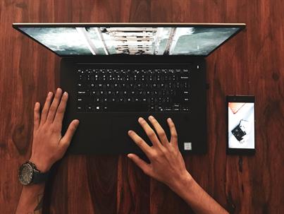 person using laptop with phone on desk
