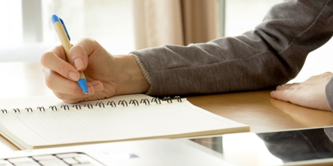 person with notepad at computer