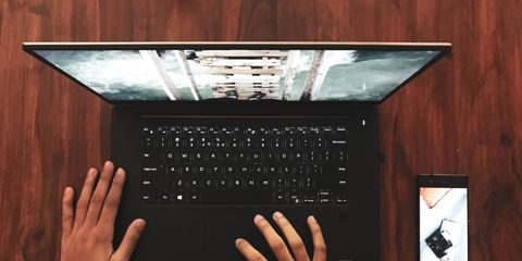 person using laptop with phone on desk