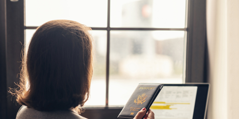 Woman holding passport filling visa application form on the laptop. Online and home work concept.