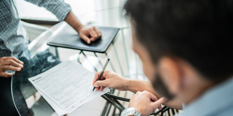 Close-up of male customer signing contract with financial advisor at home