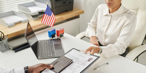 Young specialist taking document from man to make visa in visa center