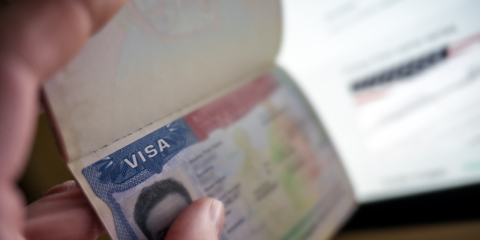 Unknown causian person holding passport with visa issued for United States of America