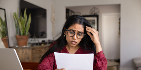 Frustrated concerned young Indian woman in glasses reading bad news in legal document, getting financial problems, rejection from university, notice from bank, touching head