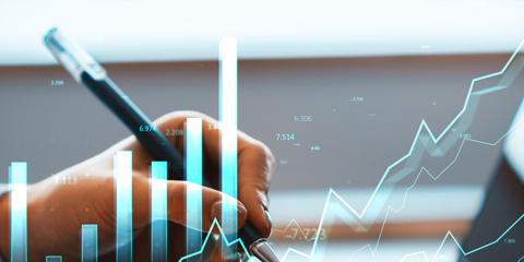 Hand writing on desk with bright financial bars and lines in soft background, concept of market growth and data analysis