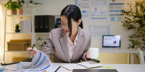 Businesswoman analyzing reports and taking notes during a productive work session in a bright workspace.