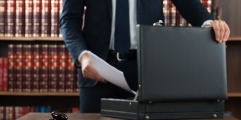 Midsection of lawyer putting documents in briefcase with gavel at desk in courtroom
