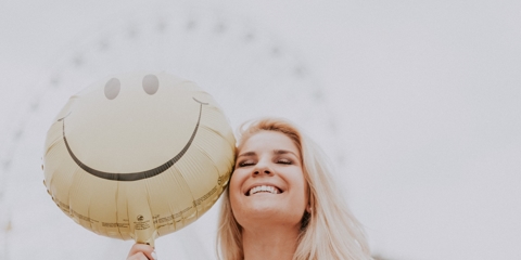 smiling person holding happy face balloon