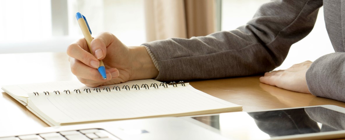 person with notepad at computer