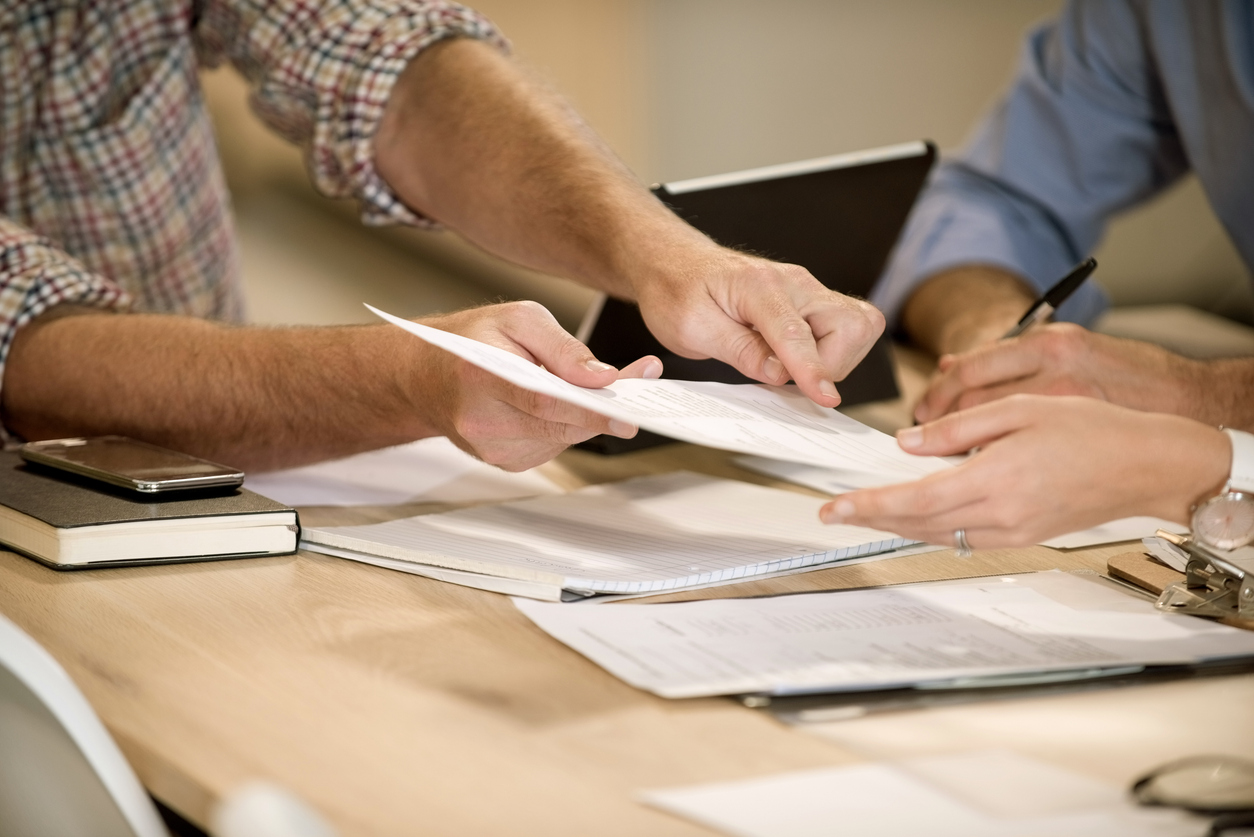 Business professional showing the place to sign on the document to female colleague. Close-up for business people signing a contract paper.
