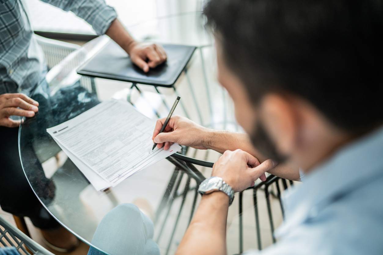 Close-up of male customer signing contract with financial advisor at home