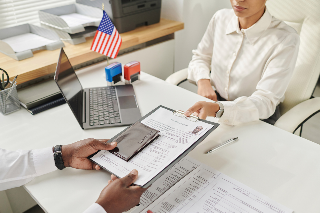 Young specialist taking document from man to make visa in visa center
