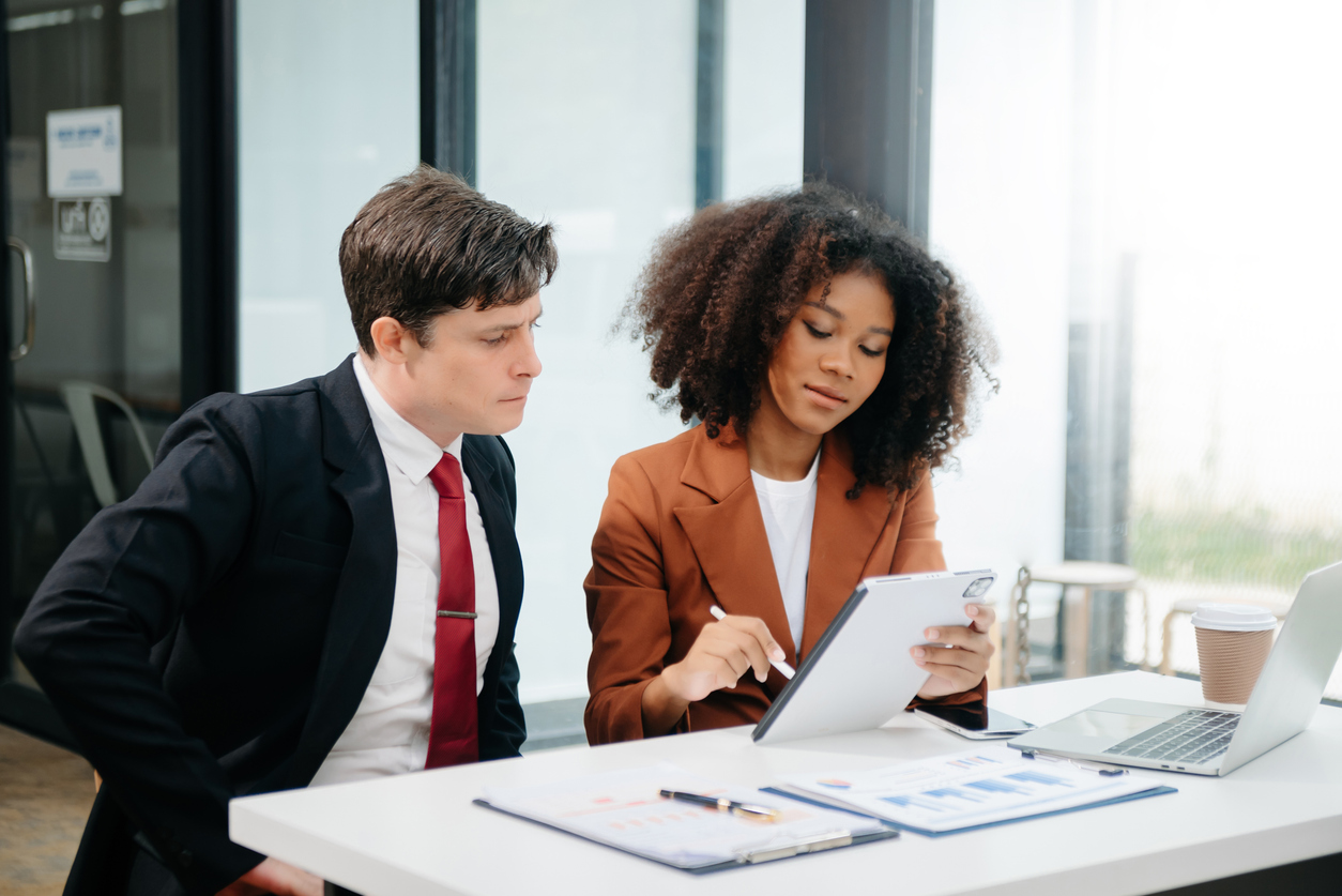 Businesswomen work and discuss their business plans. A Human employee explains and shows her colleague the results paper in office.
