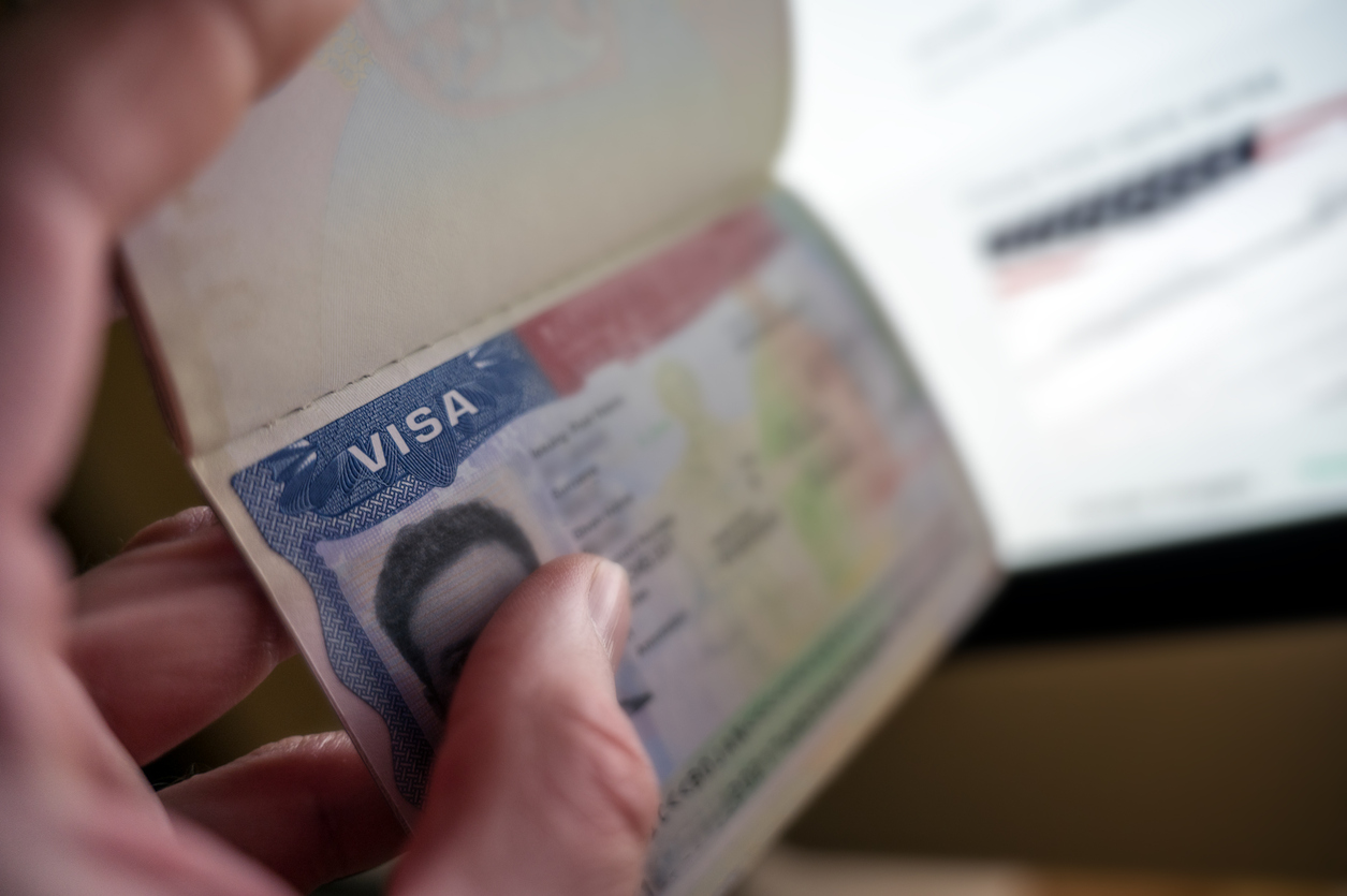Unknown causian person holding passport with visa issued for United States of America