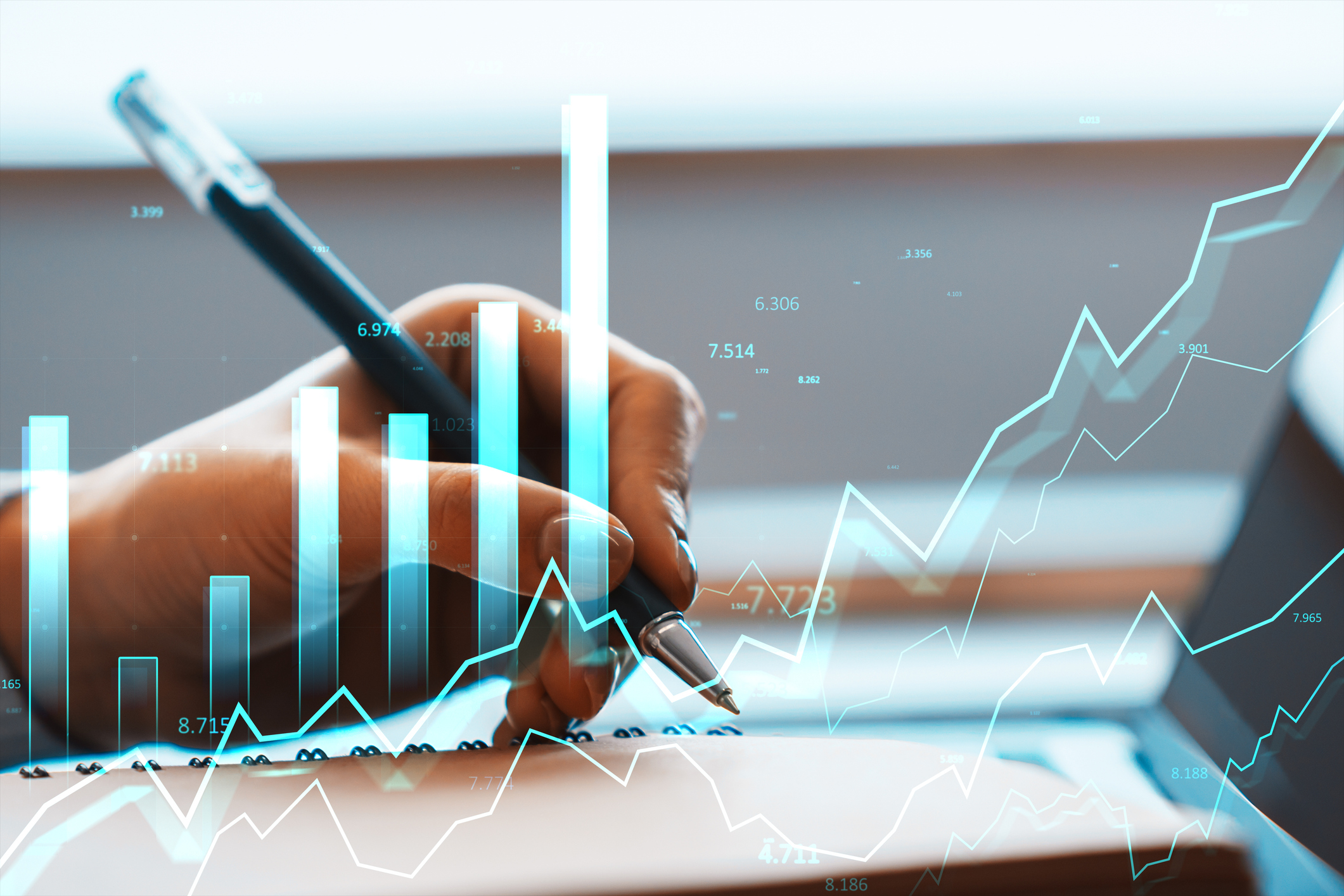 Hand writing on desk with bright financial bars and lines in soft background, concept of market growth and data analysis