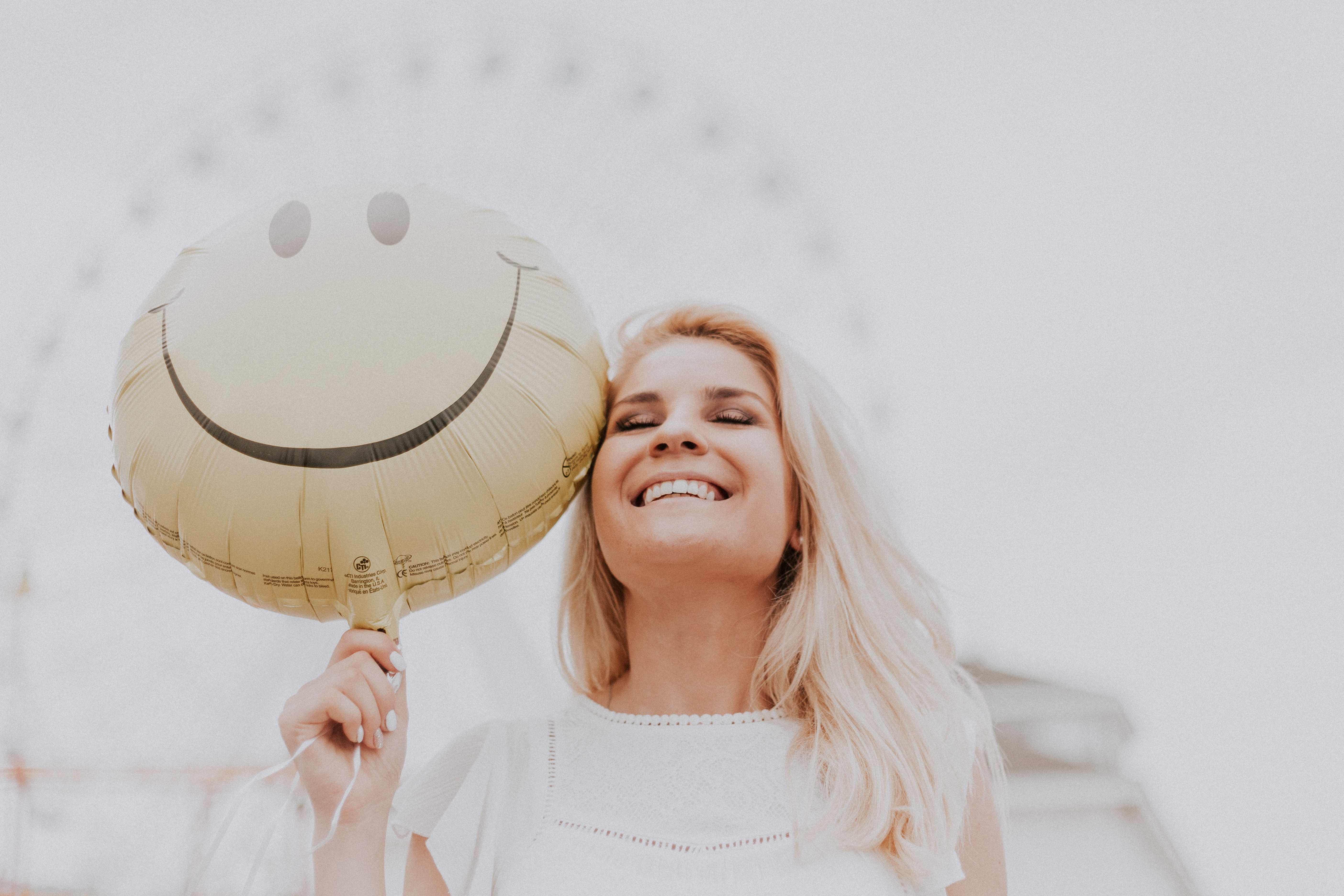 smiling person holding happy face balloon
