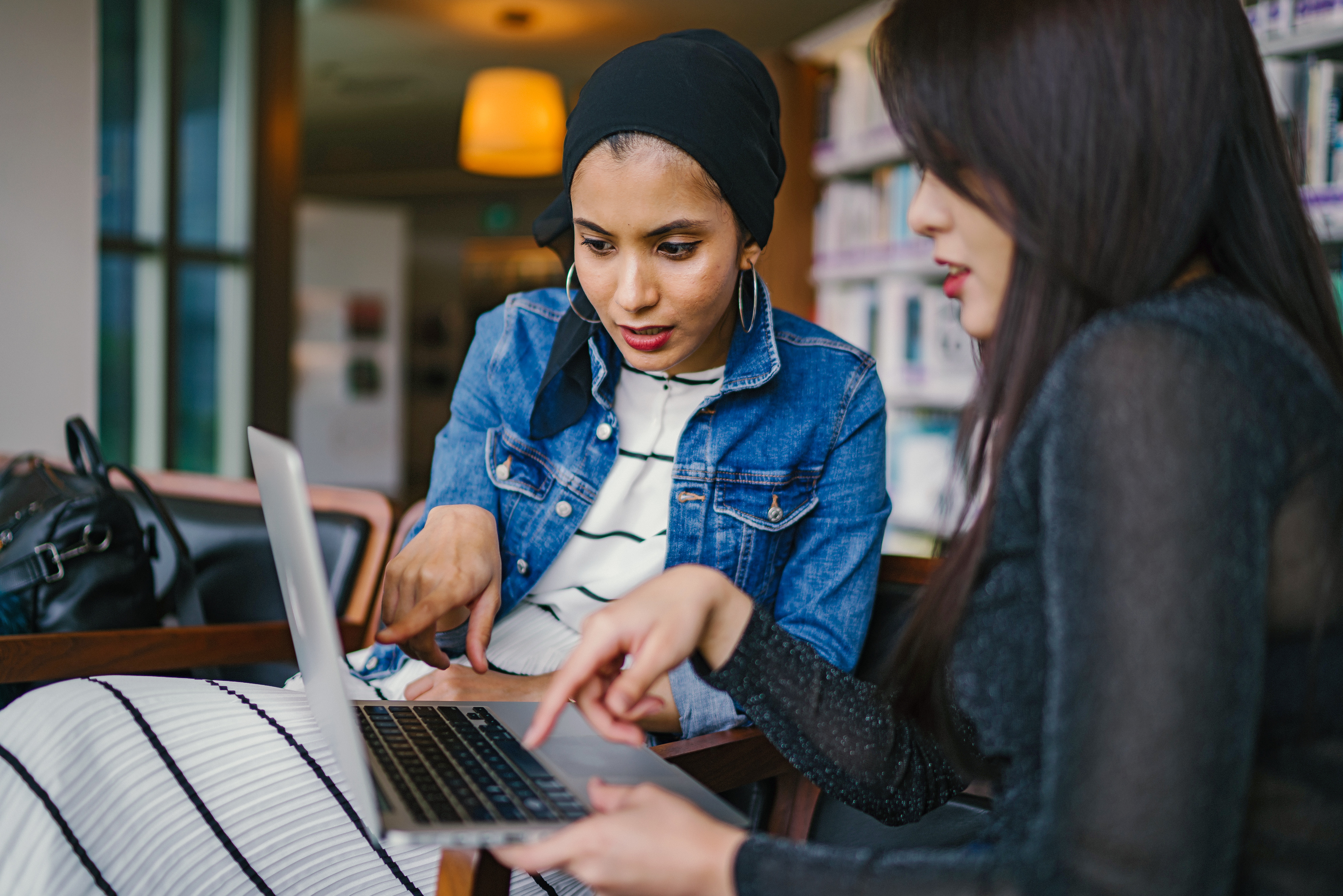 two women discussing business while pointing at laptop